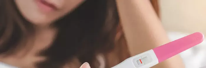 woman staring at pregnancy test